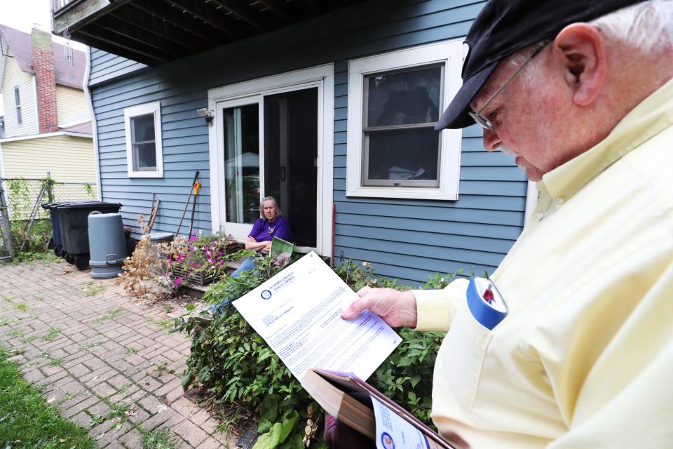 Susan Jenkins sits on a step in the back yard as her husband Lew looks over the property appraisal of their Highland Square home in Akron. The Jenkins, who are semi-retired, are concerned over their appraisal and plan to appeal.