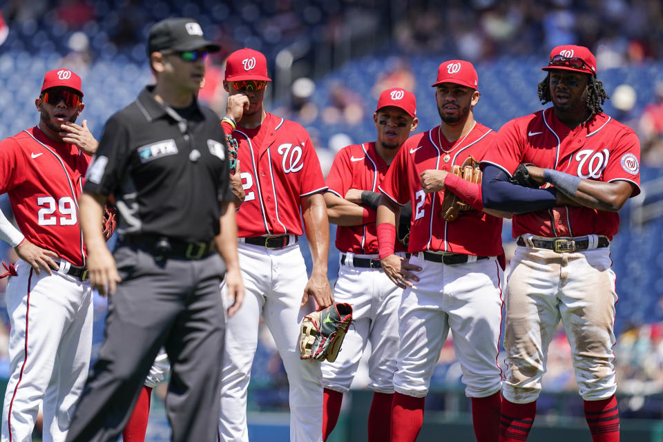 Members of the against the Washington Nationals watch as crew chief umpire Mark Wegner, second from left, decides a call during the fifth inning of a baseball game against the Pittsburgh Pirates at Nationals Park, Wednesday, June 29, 2022, in Washington. (AP Photo/Alex Brandon)