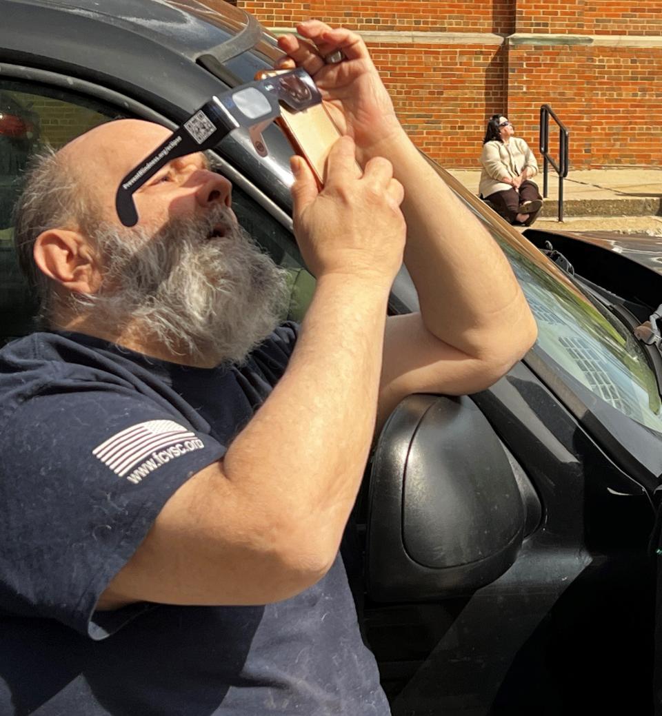 City resident Chris Petty uses his smart phone to photograph Monday's solar eclipse. He was one of around 40 people or so who watched the event at the Fairfield County District Library's main branch downtown.