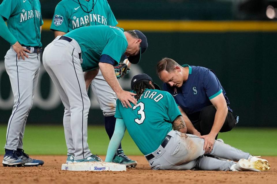 Seattle Mariners manager Scott Servais, left, and a member of the staff check on shortstop J.P. Crawford (3) after a collision between Crawford and Texas Rangers’ Leody Taveras at second during the eighth inning of a baseball game Saturday, June 3, 2023, in Arlington, Texas. Taveras was out on the play. (AP Photo/Tony Gutierrez)