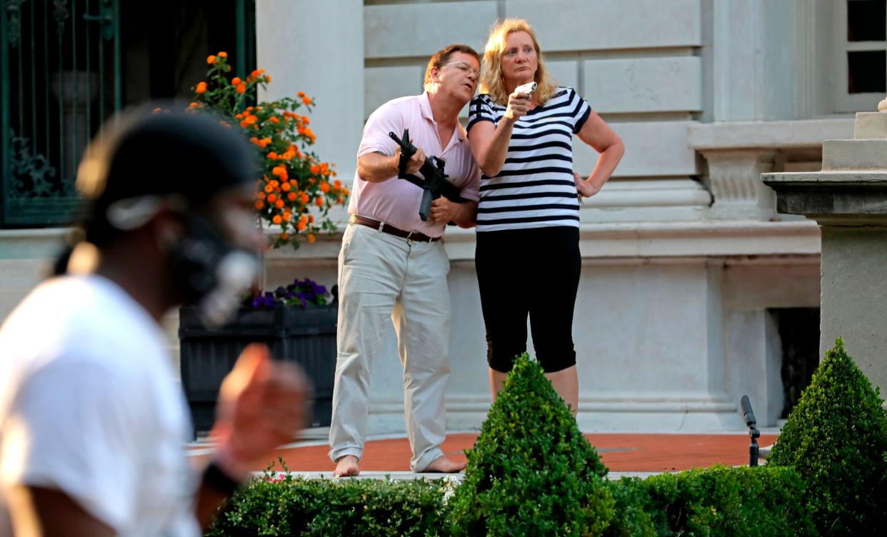 In this photo, armed homeowners Mark and Patricia McCloskey, stand in front their house confronting protesters marching to St. Louis Mayor Lyda Krewson's house in the Central West End of St. Louis on June 28, 2020. 