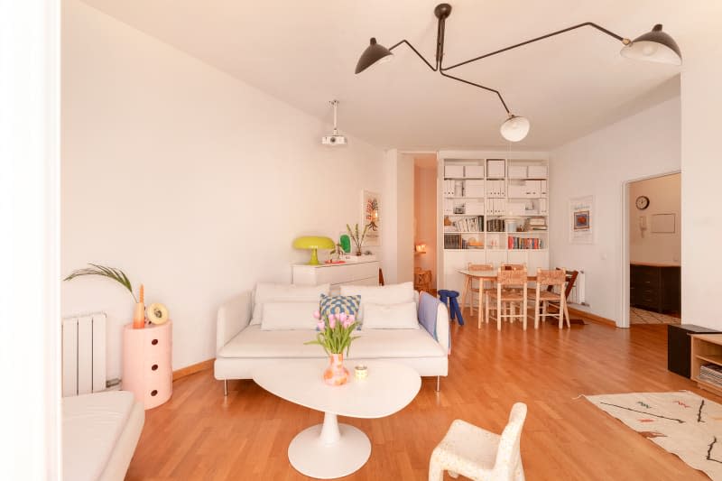 Large white living room with white sofa and dining area in the background