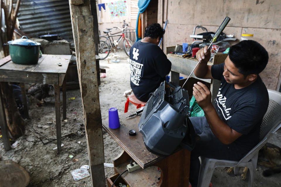 Electronics repairman Santo Francisco Acosta fixes a stereo on his porch in San Pedro Sula, Honduras, Tuesday, April 30, 2019. The U.S. government has threatened Honduras and other Northern Triangle countries with security and humanitarian aid cuts if they are unable to staunch the flow of migration to the U.S., but that could have the opposite effect if jobs and anti-poverty programs suffer. (AP Photo/Delmer Martinez)