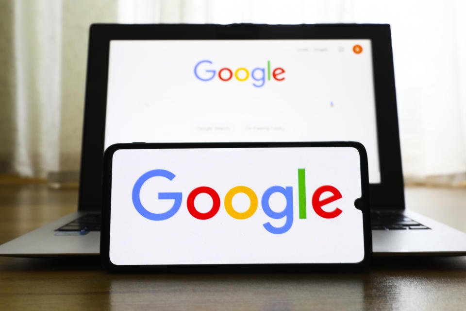 A propped-up mobile phone screen and a laptop screen display the Google logo. 