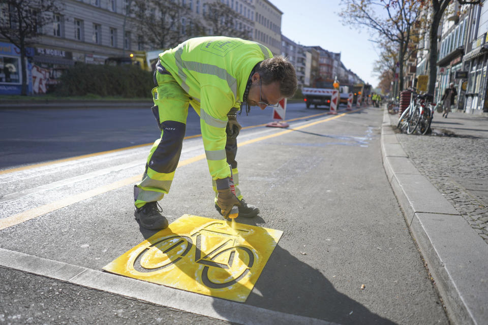 Employee Alexander of the Zeppelin company marks a temporary cycle lane on the Kottbusser Damm in Berlin, Germany, Wednesday, April 22, 2020. Due to the corona pandemic, the establishment of this bicycle lane was accelerated in order to give citizens an incentive to switch to the bicycle. The final installation of a cycle lane on Kottbusser Damm is planned for September 2020. (Joerg Carstensen/dpa via AP)