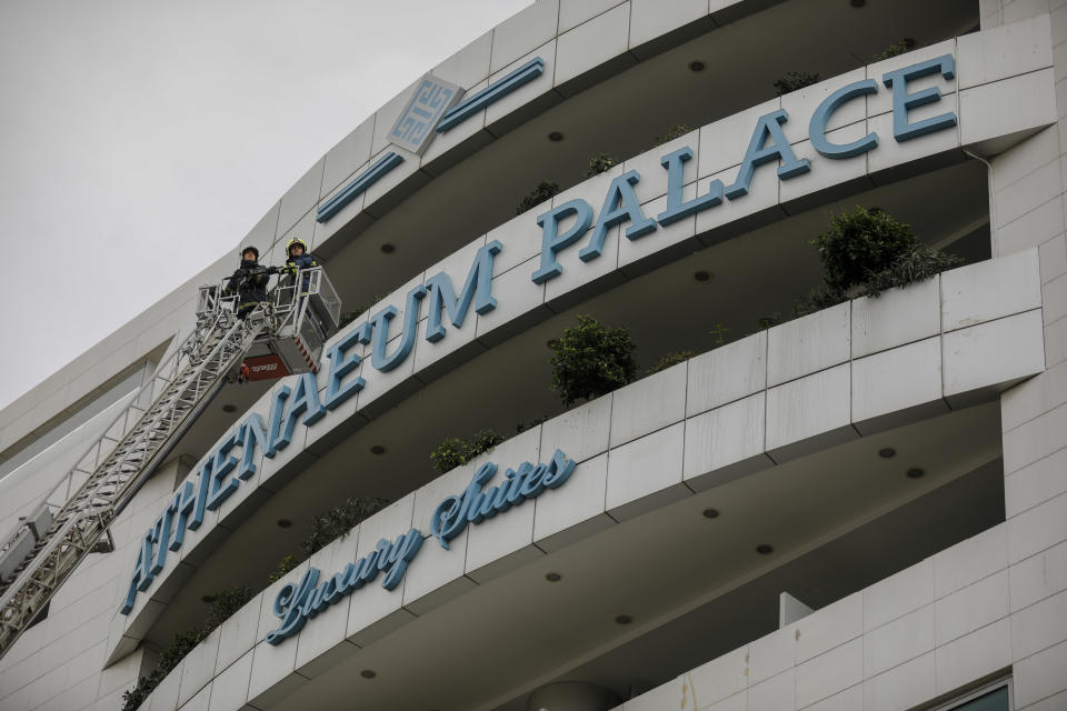 Firefighters are seen on a ladder some minutes after a fire broke up in the Athenaeum Palace hotel in Athens on Thursday, Dec. 5, 2019. A fire has broken out at a luxury hotel in the Greek capital, with fire crews evacuating the building and using ladders to rescue several people.(AP Photo/Petros Giannakouris)