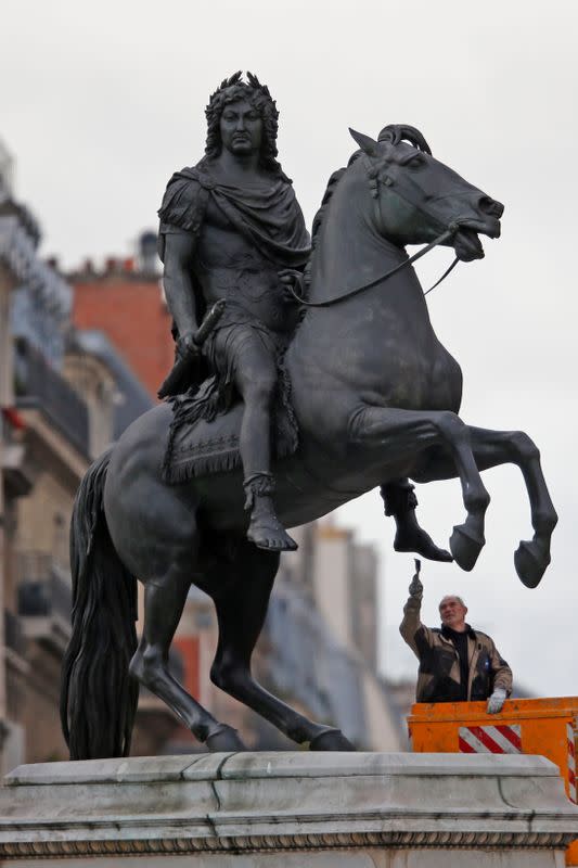 FILE PHOTO: A worker cleans up the equestrian statue of King Louis XIV of France in the center of the Place des Victoires in Paris