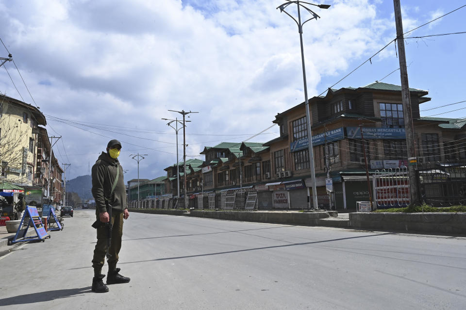 A security personnel wearing a facemask stands guard along a deserted street during a one-day nationwide Janata (civil) curfew imposed as a preventive measure against the COVID-19 coronavirus, in Srinagar on March 22, 2020. - Nearly one billion people around the world were confined to their homes, as the coronavirus death toll crossed 13,000 and factories were shut in worst-hit Italy after another single-day fatalities record. (Photo by Tauseef MUSTAFA / AFP) (Photo by TAUSEEF MUSTAFA/AFP via Getty Images)