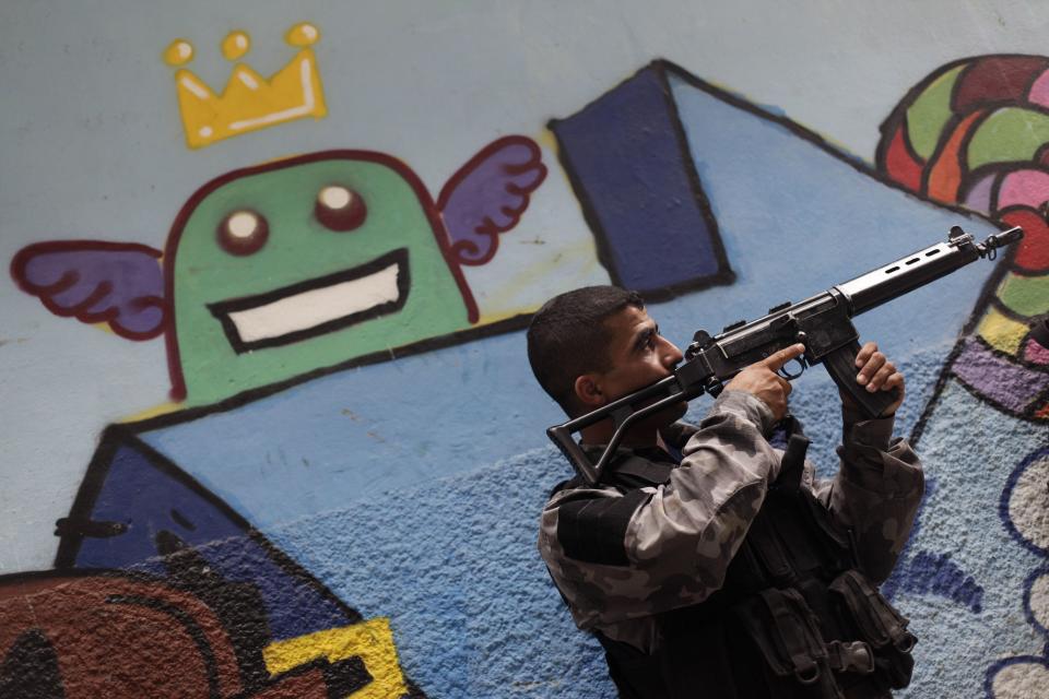 A police officer takes up position during an operation at the Mare slums complex in Rio de Janeiro