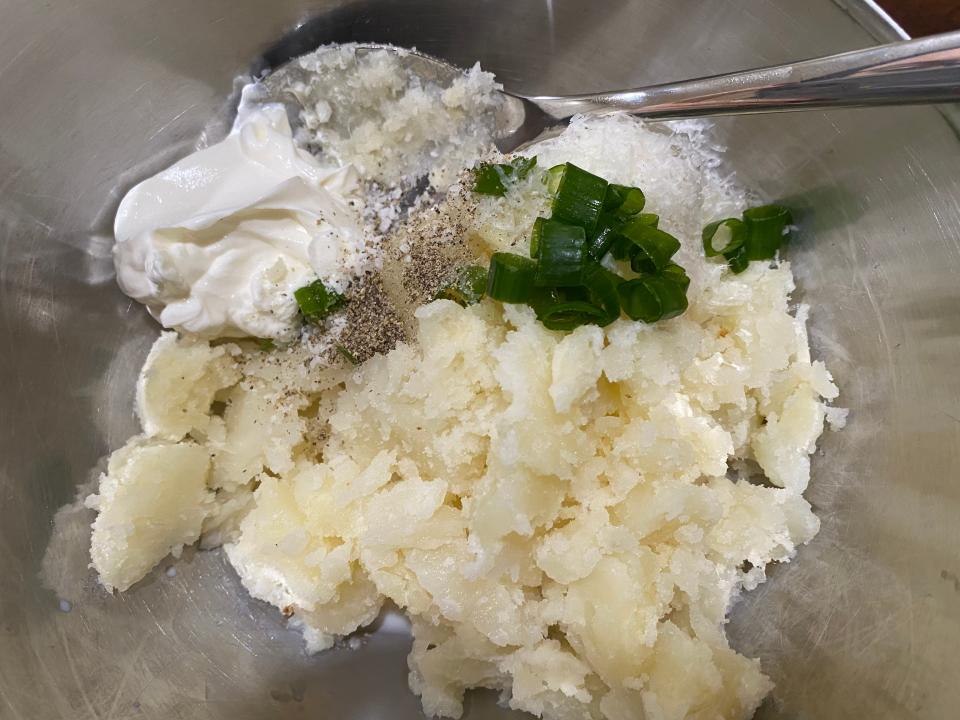 potatoes, sour cream, and onions in a mixing bowl