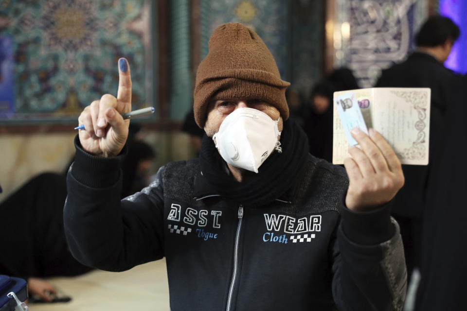 A voter shows his identification and inked finger while voting for the parliamentary elections at a polling station in Tehran, Iran, Friday, Feb. 21, 2020. Iranians began voting for a new parliament Friday, with turnout seen as a key measure of support for Iran's leadership as sanctions weigh on the economy and isolate the country diplomatically. (AP Photo/Ebrahim Noroozi)