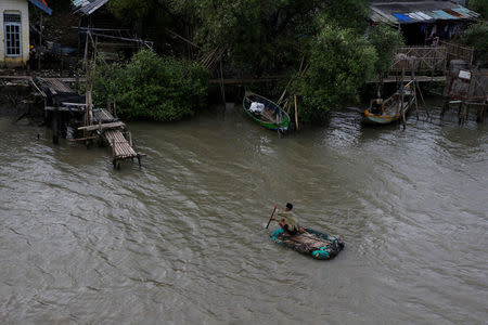 A man rows a makeshift boat to reach his house isolated by sea water at Pantai Mekar village in Bekasi, West Java province, Indonesia, January 22, 2018. REUTERS/Beawiharta