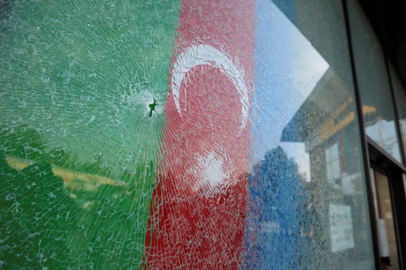 A view shows an Azerbaijani flag behind a damaged window in Barda