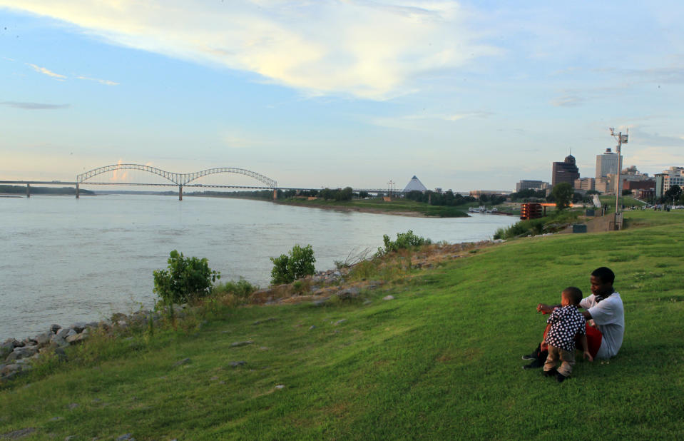 FILE - In this July 14, 2012, file photo, Marcus Milam, right, and his son Markes Milam, 3, sit along the exposed banks of the Mississippi River in Tom Lee Park, in Memphis, Tenn. The narrow, mile-long park offers great views of the river and is one of a number of free places to visit in and around Memphis. (AP Photo/Nikki Boertman)