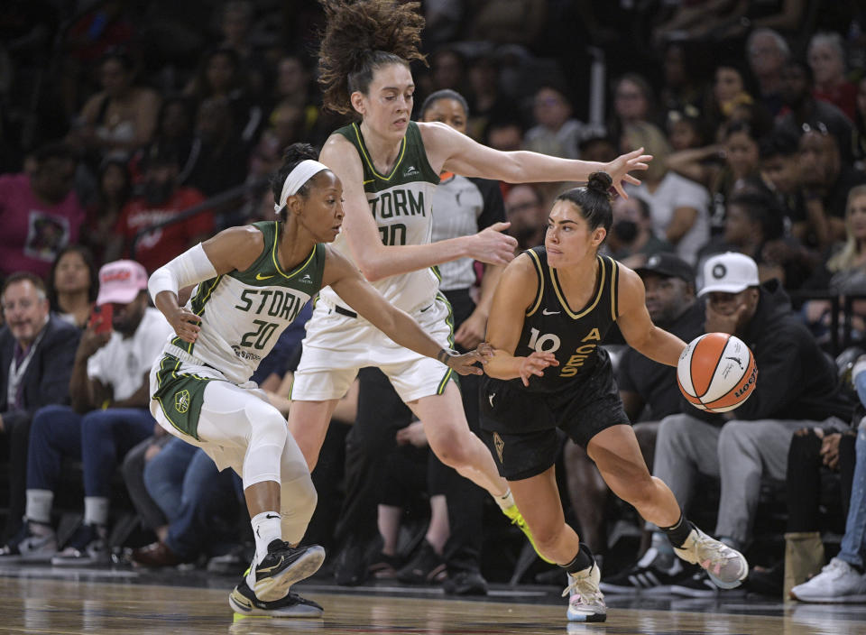 Las Vegas Aces guard Kelsey Plum (10) is defended by Seattle Storm guard Briann January (20) and forward Breanna Stewart (30) during the second half of a WNBA game Sunday, Aug. 14, 2022, in Las Vegas. (AP Photo/Sam Morris)