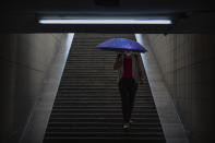 A woman wearing a face mask to protect against the coronavirus walks into the entrance of a subway station during a rainfall in Beijing, Wednesday, Aug. 5, 2020. Measures to contain the spread on a COVID-19 outbreak in China's northwestern region of Xinjiang, including locking down some communities and limiting public transport, appear to have been effective and reported case numbers have gradually fallen. (AP Photo/Mark Schiefelbein)