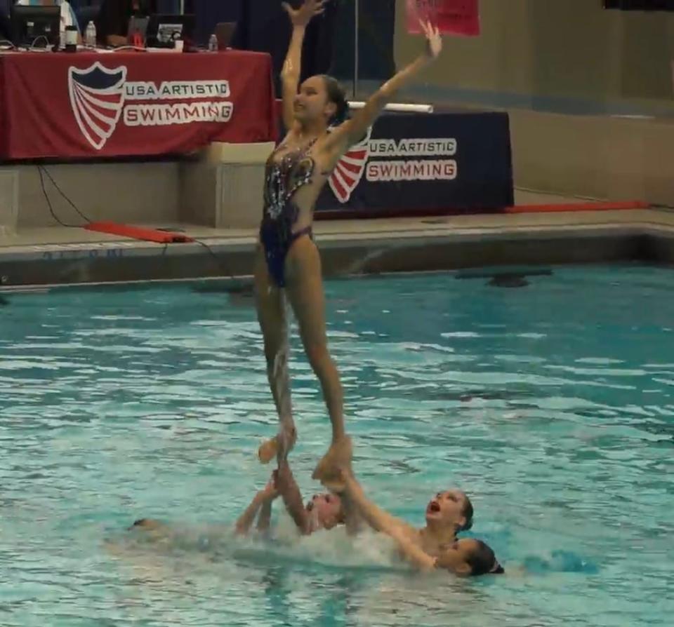 Hannah Ryou, a flyer for the Menomonee Falls Dolphinettes, is lifted by her teammates. Her teammates, left to right in the water, are Mara Stockhausen, Johanna Luo and Kathy Sun.