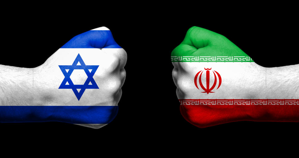 Flags of Israel and Iran painted on two clenched fists facing each other on black background/Israel - Iran conflict concept