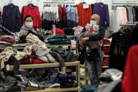 Black Friday shopper Alex Gamboa, right, 58, of Los Angeles, holds merchandises as his wife, who did not give her name, checks the bargains at the Glendale Galleria in Glendale, Calif., Friday, Nov. 27, 2020. (AP Photo/Ringo H.W. Chiu)