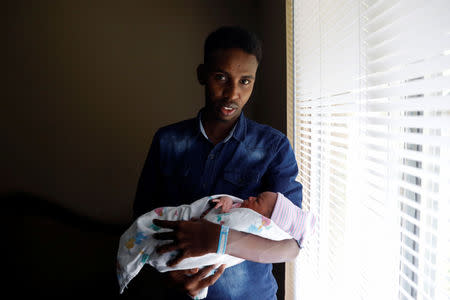 Aden Hussein Hassan holds his daughter Asmo, 2 days inside their apartment in Columbus, Ohio, U.S., August 8, 2018. REUTERS/Shannon Stapleton