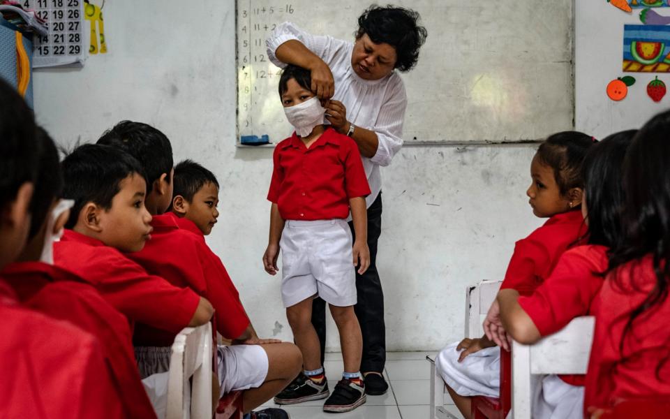 A teacher shows students how to use a mask made from tissue at the Cinta Bangsa kindergarten in Yogyakarta, Indonesia -  Ulet Ifansasti / Getty