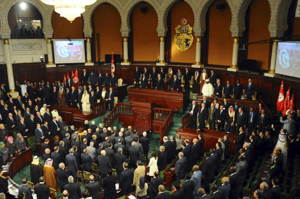 Parliament members and officials stand at the Constituent Assembly in Tunis, Friday, Feb. 7, 2014. French President Francois Hollande and other world leaders attended a ceremony for the formal adoption of a document being praised as one of the most progressive constitutions in an Arab nation. (AP Photo/Hassene Dridi)