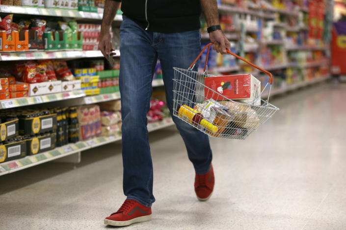 A shopper carries a basket in a supermarket in London. The FTSE was down on the day