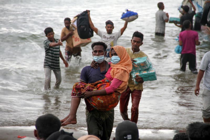 Rohingya refugees are evacuated by locals at a coast of North Aceh