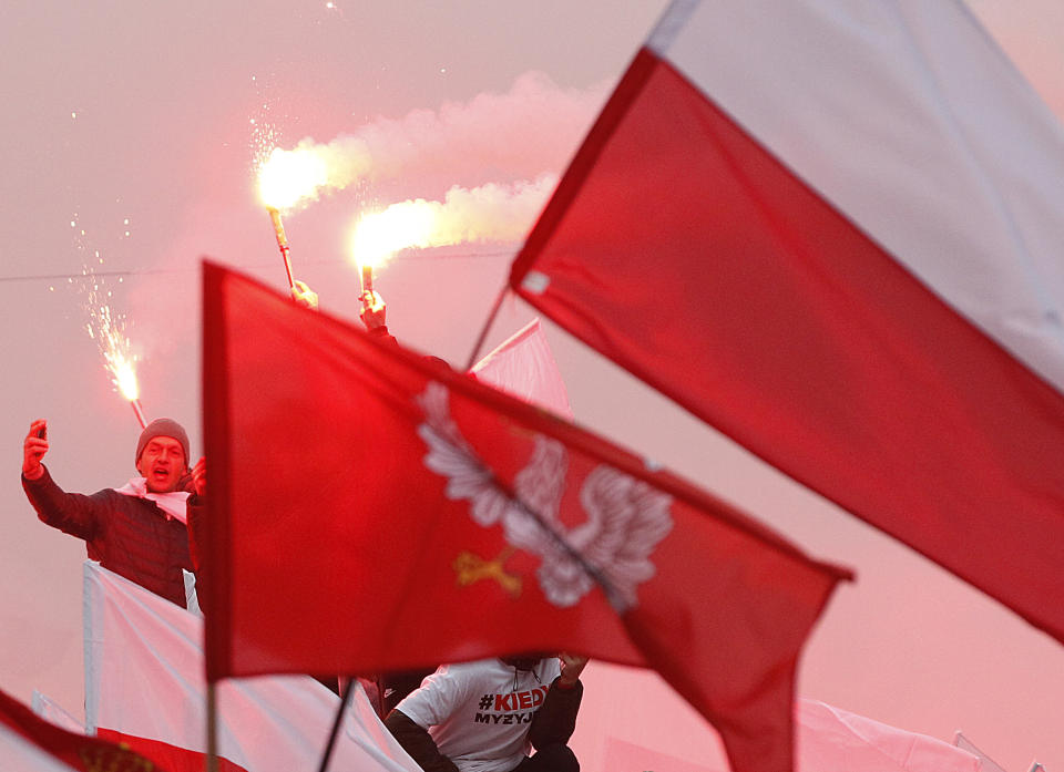 Members of right-wing groups light up flares during a march by some tens of thousands of people and hosted by President Andrzej Duda that marked 100-years since Poland regained independence, in Warsaw, Poland, Sunday, Nov. 11, 2018. (AP Photo/Czarek Sokolowski)