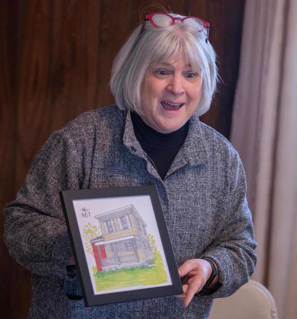 Beth Lechner, CEO of Habitat for Humanity East Central Ohio, surprises members of the Johnson family with a painting of the family home lovingly called "The 607."