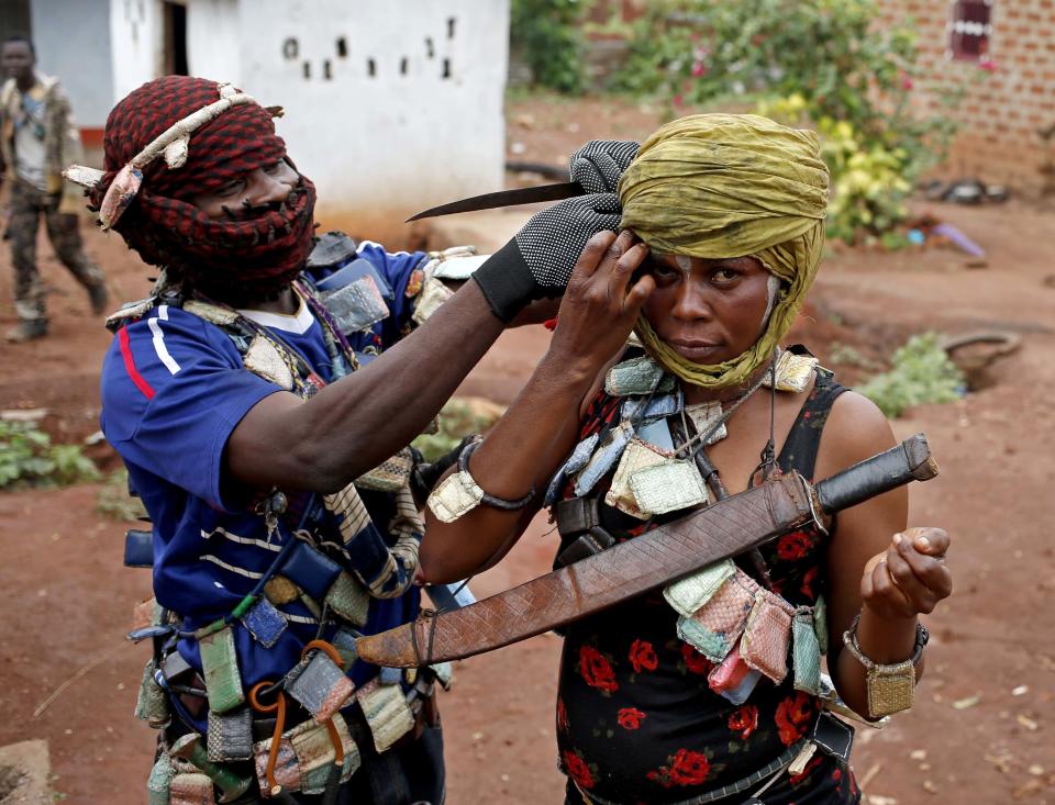 A masked member of the anti-balaka, a Christian militia, adjusts scarf of comrade before they patrol village of Zawa