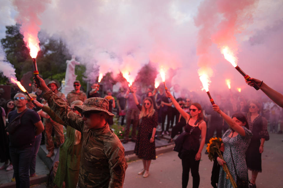 Soldiers hold flares as they attend the funeral of activist and soldier Roman Ratushnyi in Kyiv, Ukraine, Saturday, June 18, 2022. Ratushnyi died in a battle near Izyum, where Russian and Ukrainian troops are fighting for control of the area. (AP Photo/Natacha Pisarenko)