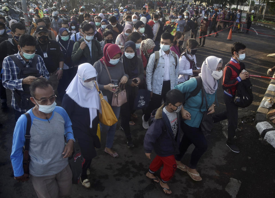 People wearing face mask to help curb the spread of coronavirus outbreak queue up to enter a commuter train station during the morning rush hour in Bekasi, Indonesia, Monday, Jan. 25, 2021. (AP Photo/Achmad Ibrahim)