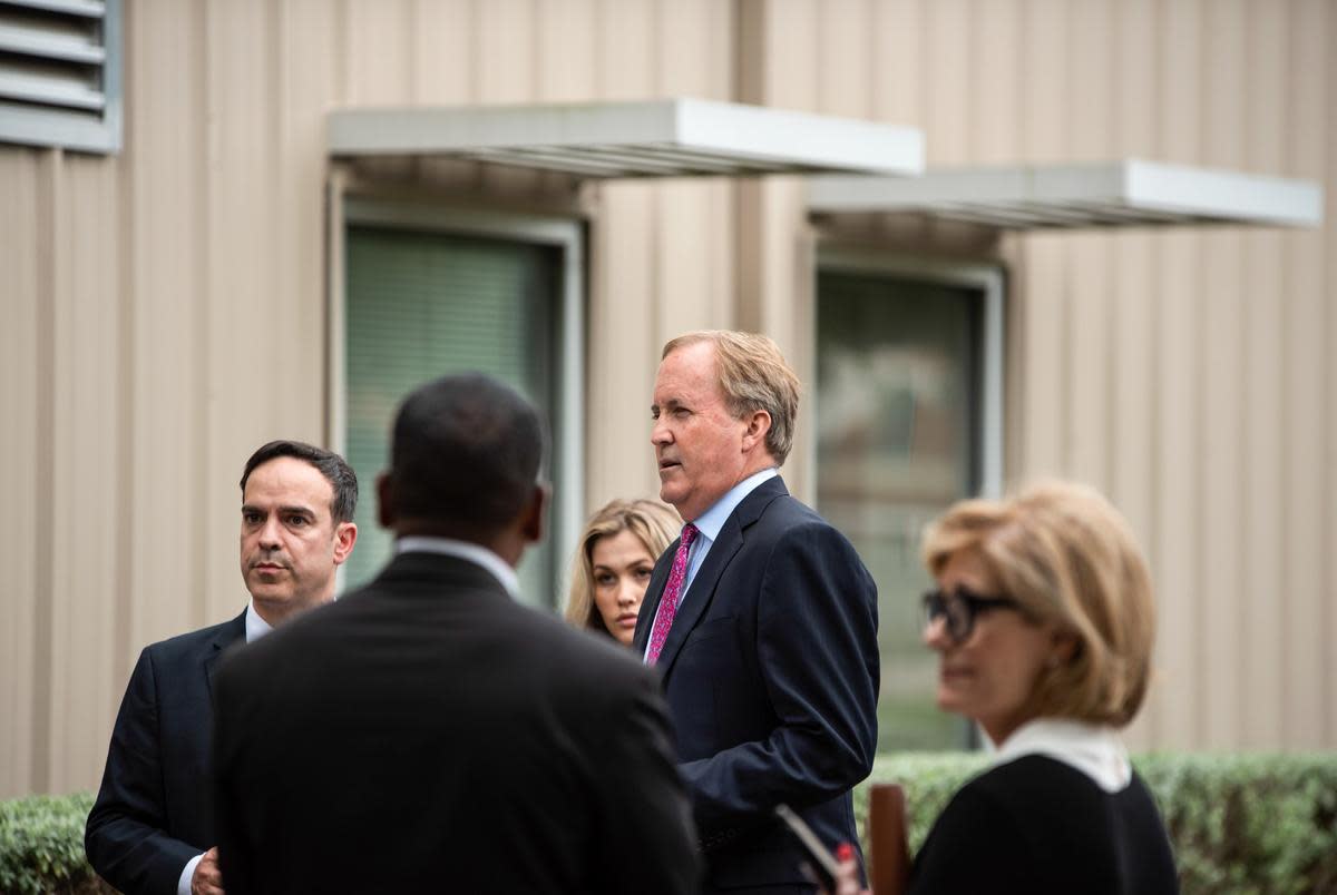 State Attorney General Ken Paxton, right, talks with staff members before a press conference at the Houston Recovery Center on October 26, 2021.