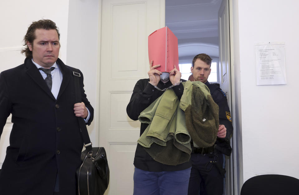 A 31-year-old American man accused of murder, center, is led into the courtroom at the regional court in Kempten, Germany, Monday March 11, 2024. An American man was convicted of murder and other charges on Monday for brutally attacking two American women at a tourist site in southern Germany last summer and pushing them into a ravine, fatally injuring one of them. He was sentenced to life in prison. (Karl-Josef Hildenbrand/dpa via AP)