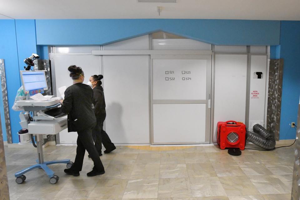 Health care workers make their way past a sealed-off suite at Wolfson Children's Hospital where pediatric COVID-19 patients who are not in the intensive care unit are treated.