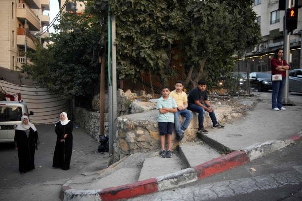 Palestinian youth sit on a street on 24 October 2023 in the West Bank city of Ramallah (AFP via Getty Images)