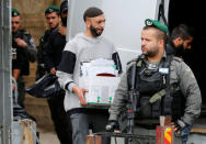 An undercover Israeli security officer carries a box containing documents seized from a Palestinian map office by Israeli security officers as they carry out an Israeli police order to close the office, in the Arab East Jerusalem neighbourhood of Beit Hanina March 14, 2017. REUTERS/Ammar Awad