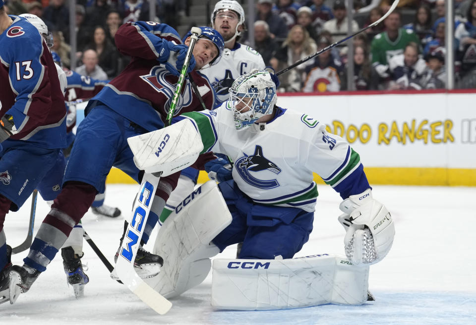 Colorado Avalanche right wing Mikko Rantanen, left, becomes entangled with Vancouver Canucks goaltender Thatcher Demko during the first period of an NHL hockey game Wednesday, Nov. 22, 2023, in Denver. (AP Photo/David Zalubowski)