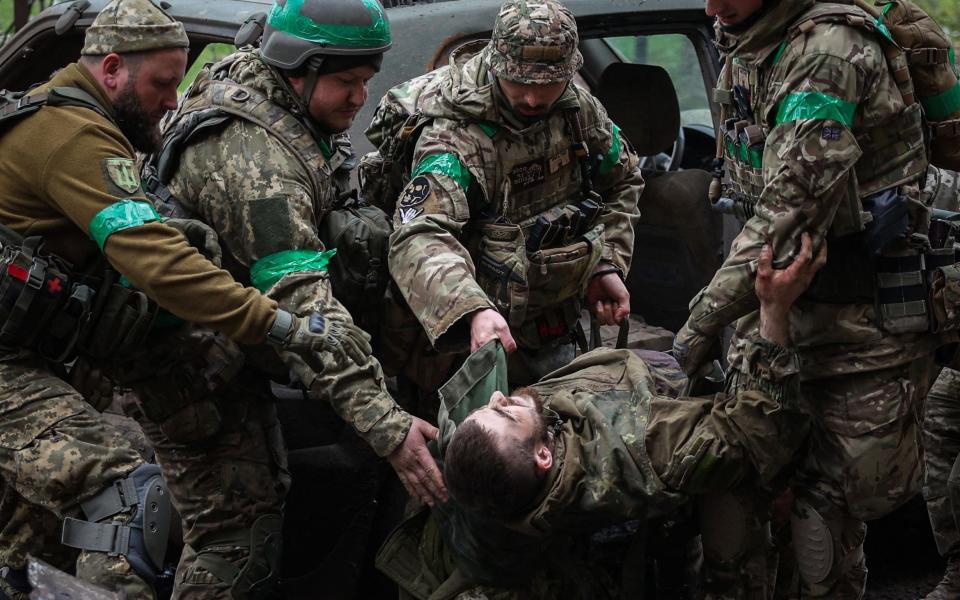 Ukrainian servicemen carry an injured comrade on a street in the frontline city of Bakhmut, Donetsk region - ANATOLII STEPANOV/AFP