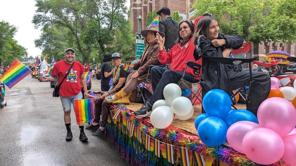 Prestin Thôtin-Awâsis, left, walks alongside the leading float in the 2024 Saskatoon Pride Parade.