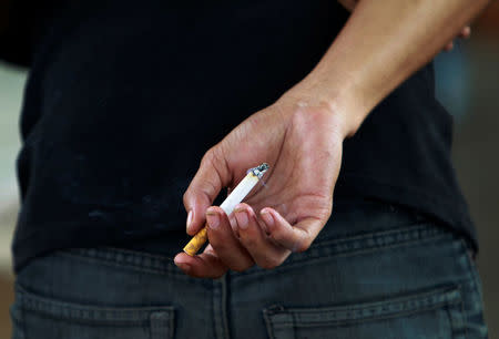 An Indonesian youth holds a cigarette while waiting for a train in Jakarta May 24, 2012. REUTERS/Beawiharta/File Photo