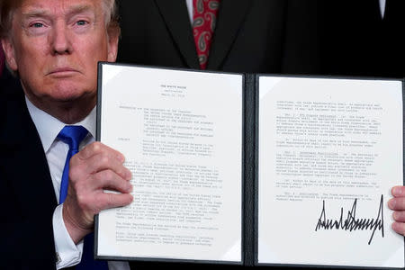 FILE PHOTO: U.S. President Donald Trump holds a signed memorandum on intellectual property tariffs on high-tech goods from China, at the White House in Washington, U.S. March 22, 2018. REUTERS/Jonathan Ernst