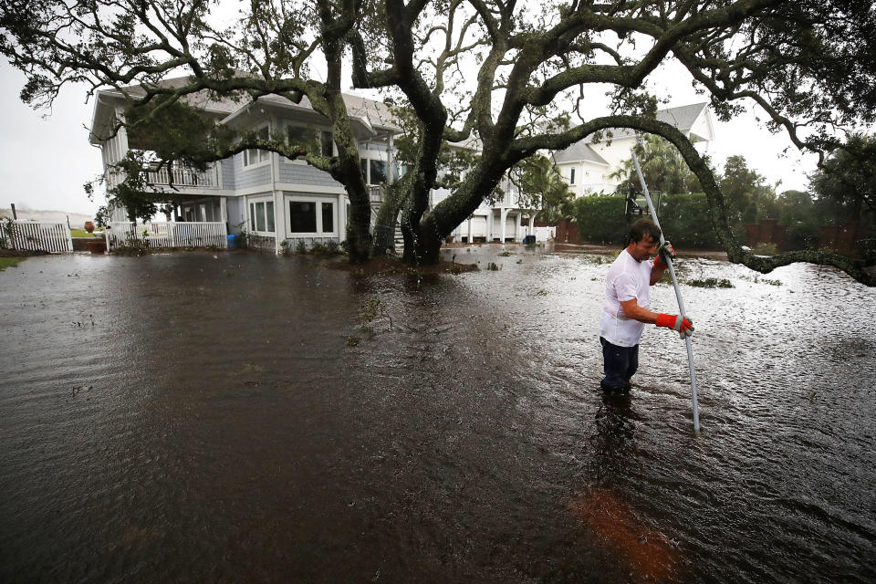 Mike Pollack searches for a drain in the yard of his flooded waterfront home in Wilmington.