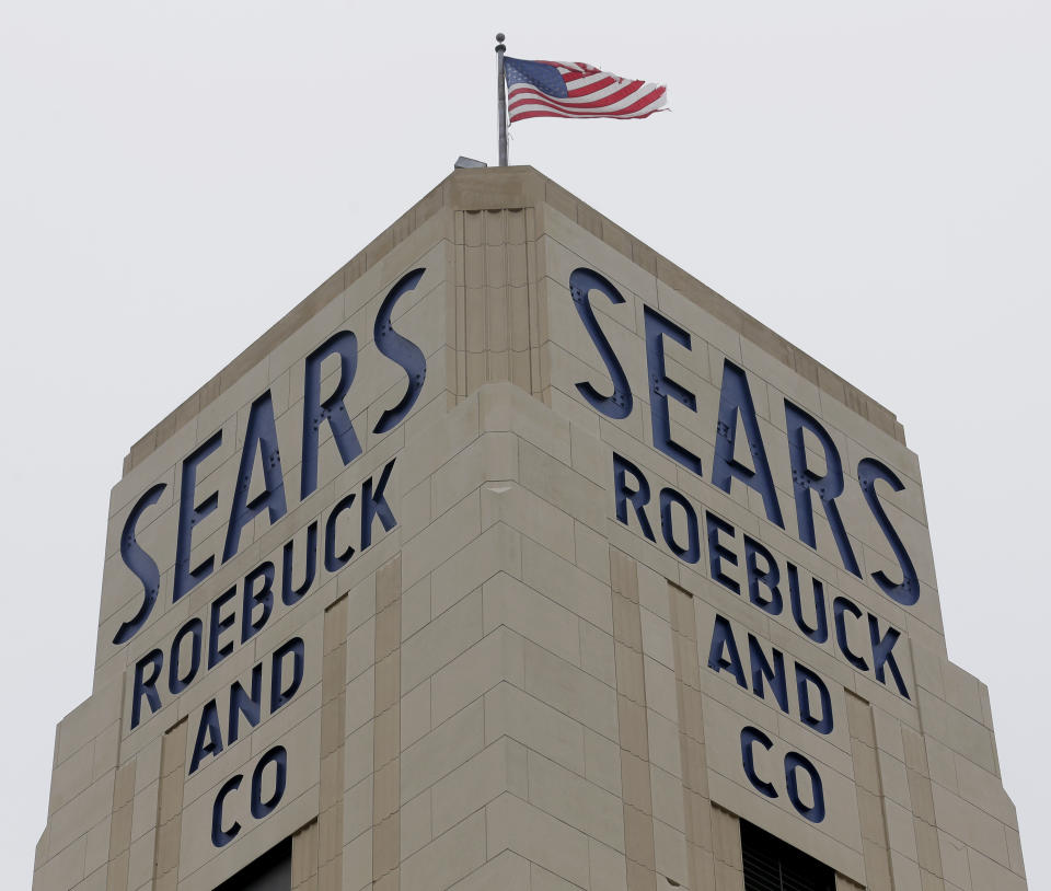 FILE- In this Jan. 8, 2019, file photo an American flag flies above a Sears store in Hackensack, N.J. A bankruptcy judge has blessed a $5.2 billion plan by Sears chairman and biggest shareholder Eddie Lampert to keep the iconic business going. The approval means roughly 425 stores and 45,000 jobs will be preserved. (AP Photo/Seth Wenig, File)