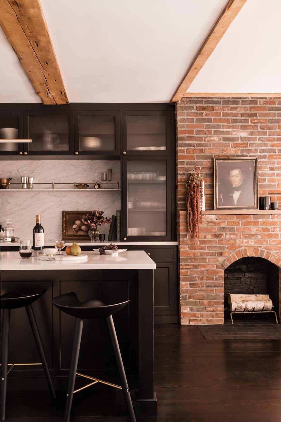 AFTER: Dana took down the wall between the dining room and kitchen, exposed the brick chimney in the dining area, covered some of the brick with cabinetry, and rethought the beams. “Only every fourth beam is exposed now,” the designer says. “It was an exercise in portion control.”