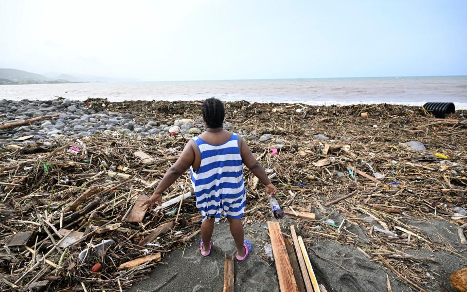 A woman looks at a beach strewn with rubbish in Bull Bay, Jamaica, after Hurricane Beryl