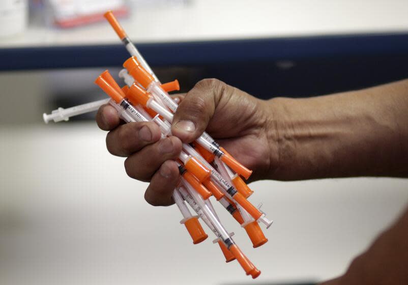 In this Monday, May 6, 2019 photo, Jose Garcia, an injection drug user, deposits used needles into a container at the IDEA exchange, in Miami. The University of Miami pilot program allows users to exchange used syringes for clean ones in order to avoid the transmission of HIV, Hepatitis C and other blood-borne diseases. Needle exchanges could eventually come to other parts of the state under a new law signed by Gov. Ron DeSantis. (AP Photo/Lynne Sladky)