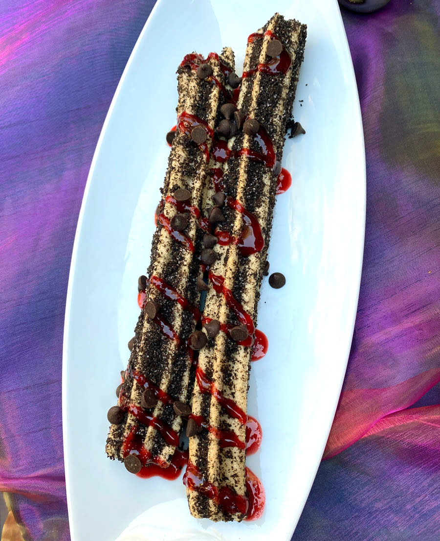 Two churro sticks covered in chocolate and cherry glaze