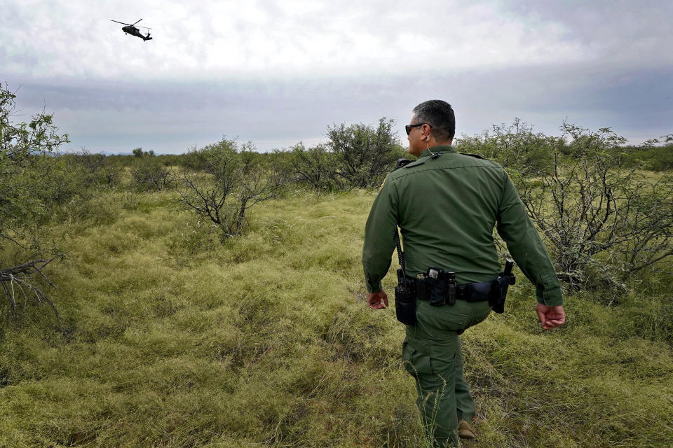 U.S. Border Patrol agent Jesus Vasavilbaso, aided by a Black Hawk helicopter, searches for a group of migrants evading capture in the desert brush at the base of the Baboquivari Mountains, Thursday, Sept. 8, 2022, near Sasabe, Ariz. The desert region located in the Tucson sector just north of Mexico is one of the deadliest stretches along the international border with rugged desert mountains, uneven topography, washes and triple-digit temperatures in the summer months. Border Patrol agents performed 3,000 rescues in the sector in the past 12 months. (AP Photo/Matt York)